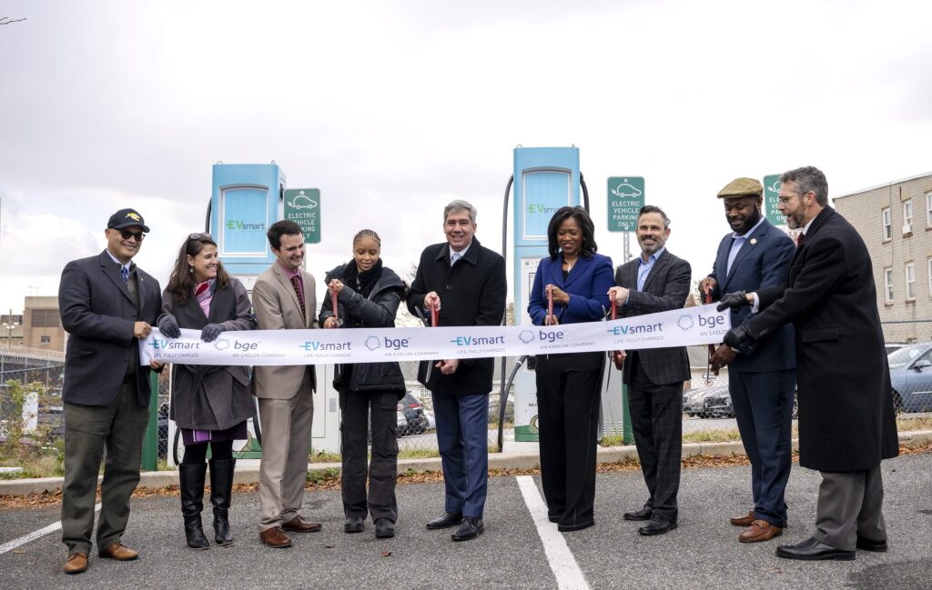 group of people cutting a ribbon in front of two EV charging stations