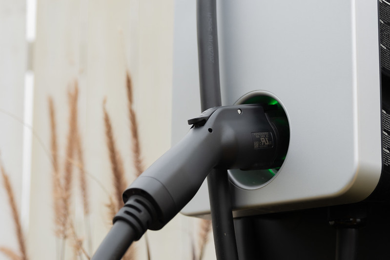 Image of a port in a charging station. The inner ring glows green and there is grass in the background.