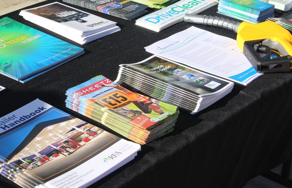 A table of fliers and a yellow gasoline pump handle.